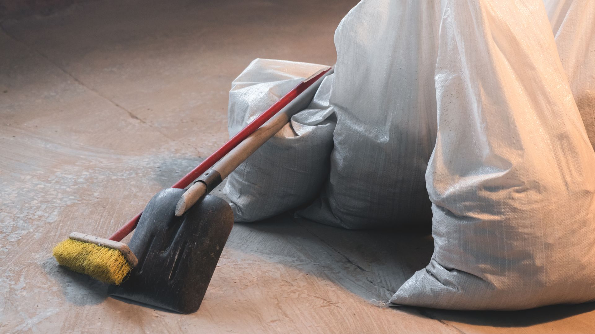 Dustpan and brush with gray cleaning bags on wooden floor