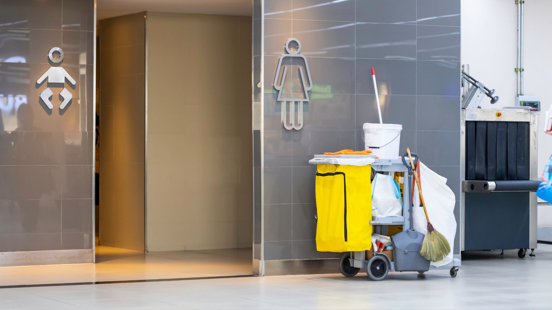 Bathroom with baby changing icon and janitorial cleaning cart nearby
