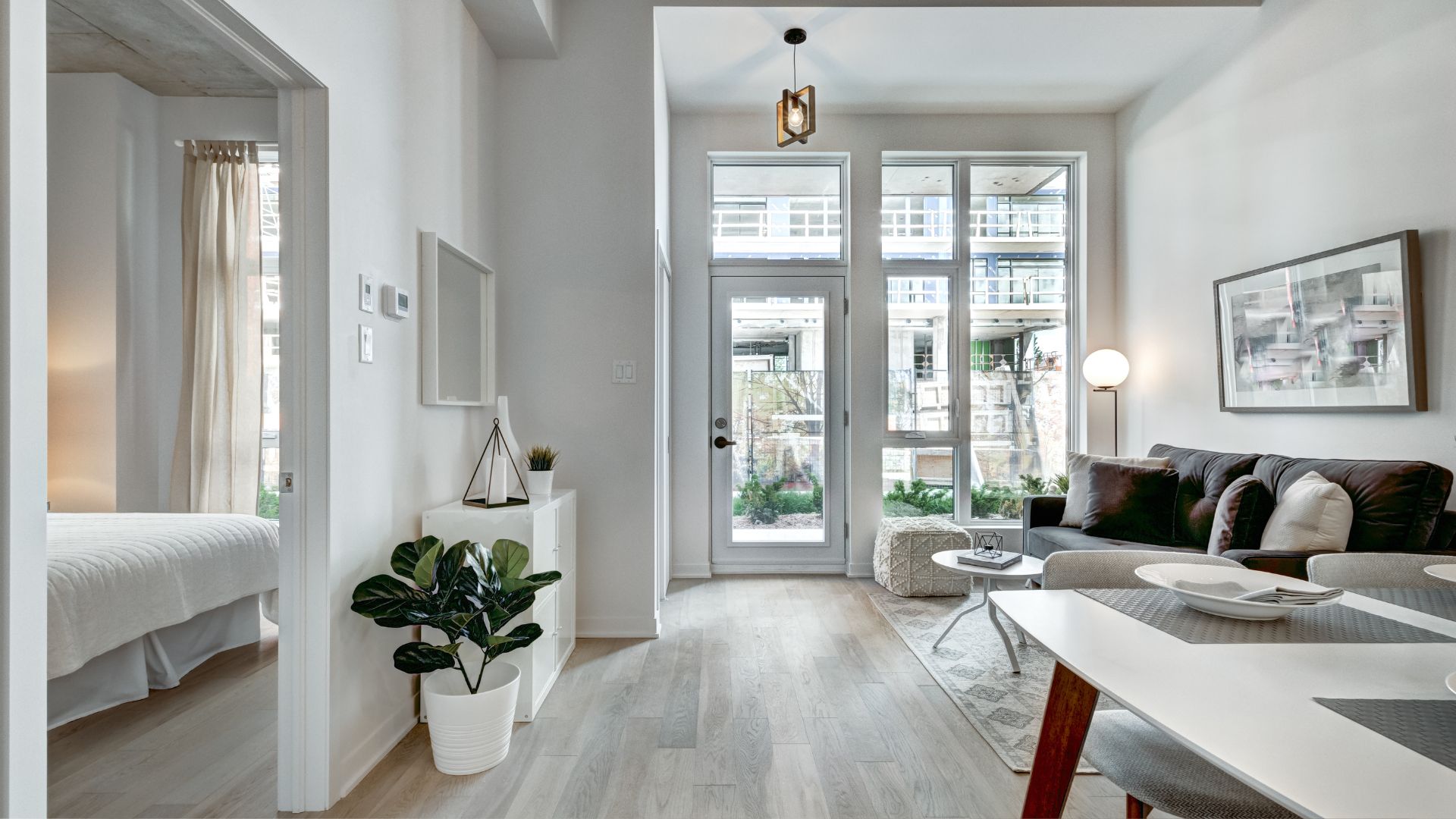 Modern minimalist apartment with white walls, plants, and large windows