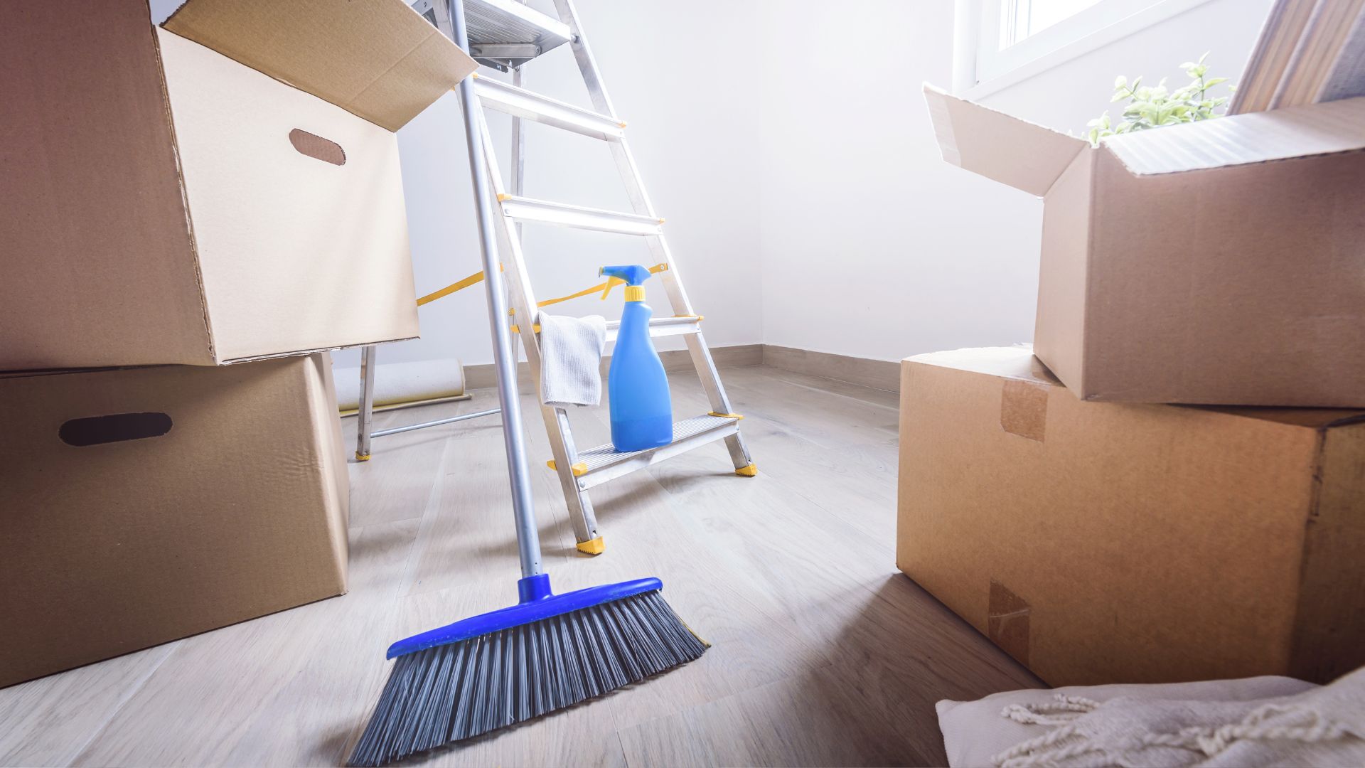Moving boxes, ladder, cleaning supplies in an empty room
